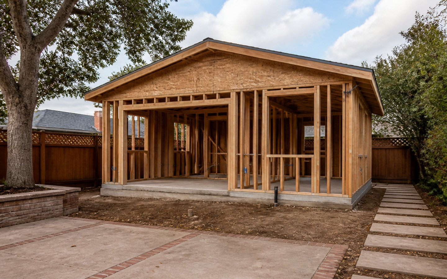 ADU Construction during planning visualization of the same space: The new slab and framing establish the ADU footprint, roof, slider, windows, structure, and weather-protection sequence.