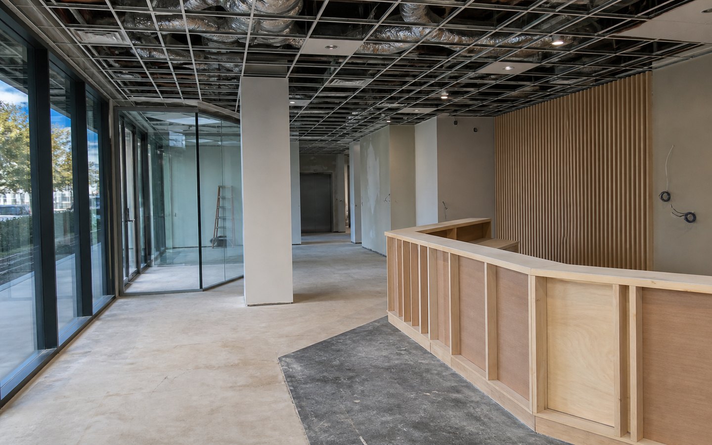 Commercial Remodeling during planning visualization of the same space: The new reception desk, glass meeting room, feature wall, central path, ceiling, data, and floor work establish the redesigned lobby.