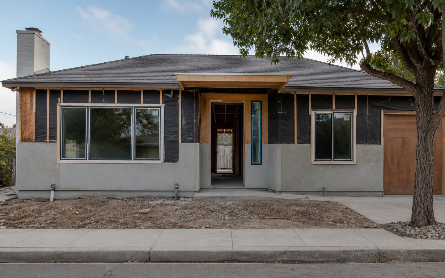 Exterior and Interior Upgrades during planning visualization of the same space: The enlarged windows, wider door and sidelight, canopy, weather barrier, and trim blocking establish the redesigned facade.